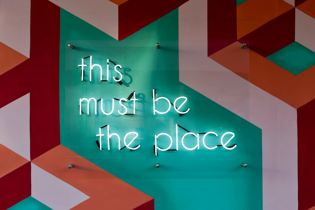 Colorful geometric wall featuring a glowing neon sign with an inspirational quote.